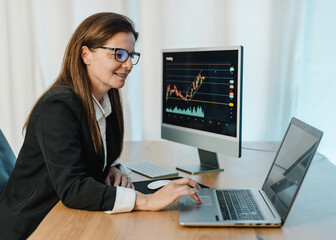 Smiling female trader working on laptop