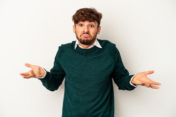 Young mixed race man isolated on grey background doubting and shrugging shoulders in questioning...