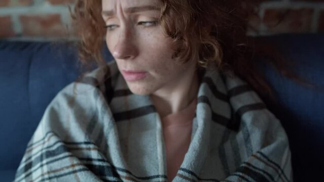 Front view of caucasian young woman covered with a blanket falling down on sofa. Shot with RED helium camera in 8K. 