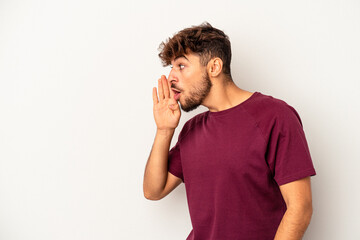 Young mixed race man isolated on grey background is saying a secret hot braking news and looking...