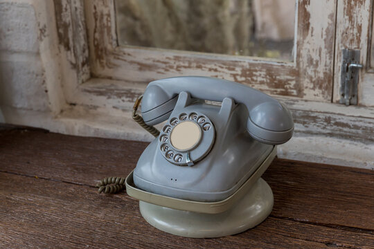 Retro rotary telephone on wood table. Vintage telephone. grey old phone. Retro telephone on table in front windows background.