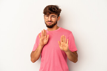 Young mixed race man isolated on grey background rejecting someone showing a gesture of disgust.