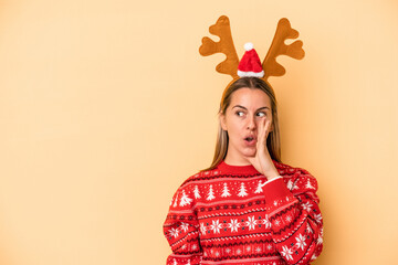 Young caucasian woman wearing a christmas reindeer hat isolated on yellow background is saying a...