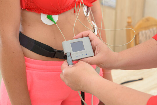 electrocardiography ECG leads for a portable heart monitor on an young woman patient. the nurse connects the ECG device to the patient