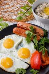 English breakfast. fried eggs with sausages and tomatoes and oatmeal with butter