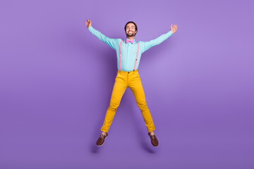 Full length photo of hipster millennial guy jump wear tie suspenders shirt pants sneakers isolated on purple background
