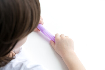 A little happy child girl plays with a pop tube fidget toy. Anti-stress sensory pop tube plastic toy in a kids hands.