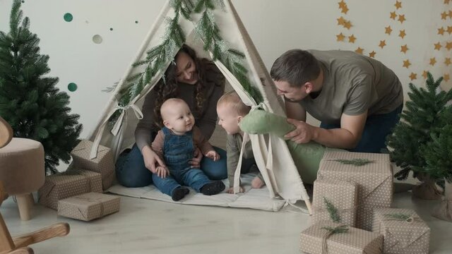 Young Father and Mother Playing with Children in Nursery Room Decorated for Xmas. Slow Motion. Happy Family, Christmas and New Year Celebration Concept