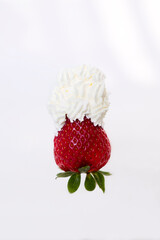 A single strawberry on white background with whipped cream on top