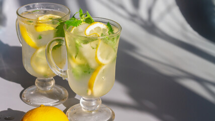 Lemon mojito drink with mint leaves in glasses on a gray background with clear shadows