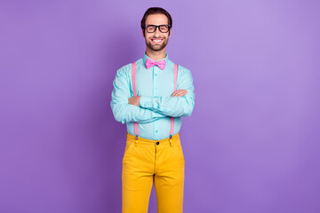 Photo of cool young brunet man crossed hands wear tie suspenders blue shirt spectacles isolated on violet color background