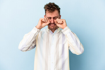 Young caucasian man isolated on blue background whining and crying disconsolately.