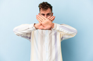 Young caucasian man isolated on blue background doing a denial gesture