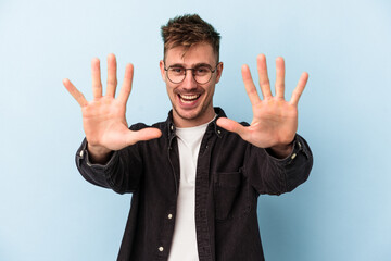 Young caucasian man isolated on blue background showing number ten with hands.