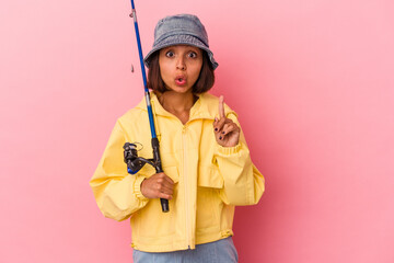 Young mixed race woman practicing fishing isolated on pink background having some great idea, concept of creativity.