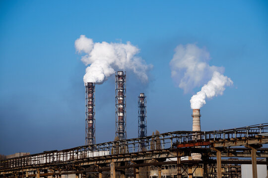 Smoke stack over chemical plant on blue sky background