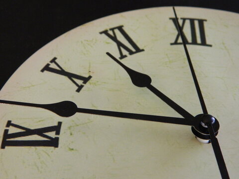 Close up of a clock face with Roman Numerals and the hour, minute and second hand 