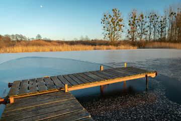 Wooden pier and a frozen lake on a winter evening