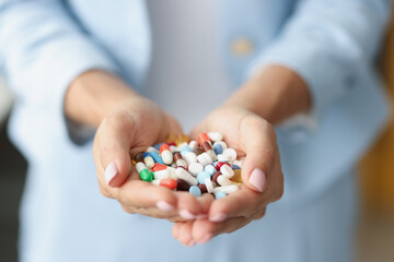Woman holding bunch of colourful medications on palm for treatment