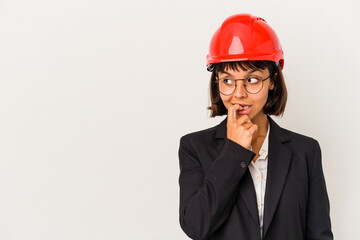 Young architect woman with red helmet isolated on white background relaxed thinking about something looking at a copy space.