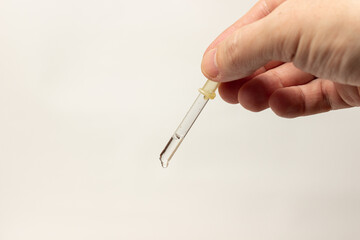 hand holds a pipette with medicine on a white background 