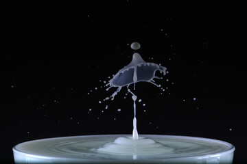 A drop of milk falls into a cup