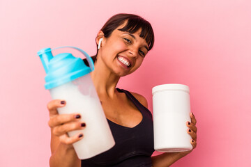 Young mixed race woman drinking a protein shake isolated on pink background