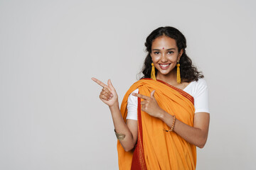 Young south asian woman wearing sari smiling while pointing finger aside