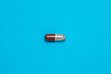 Close-up Capsule pill with granules on a Blue  Paper  background.