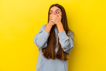 Young caucasian woman isolated on yellow background thoughtful looking to a copy space covering mouth with hand.