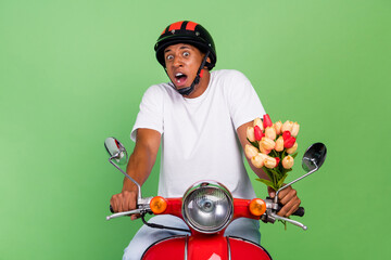 Photo of young afro man afraid scared worried hold bunch of tulips ride motor bike isolated over...