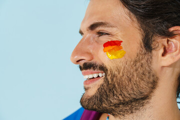 Young shirtless man with rainbow flag smiling and looking aside