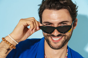 Young man wearing sunglasses laughing and looking at camera