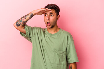 Young caucasian man with tattoos isolated on yellow background  looking far away keeping hand on forehead.