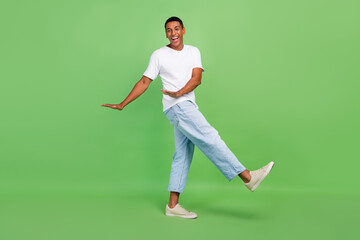 Full size profile side photo of young cheerful afro guy have fun playful go dance isolated over green color background