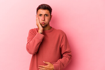 Young caucasian man with tattoos isolated on yellow background  blows cheeks, has tired expression....