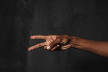 Photo of black man's hand showing peace gesture at camera