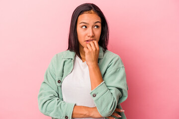 Young latin woman isolated on pink background  biting fingernails, nervous and very anxious.