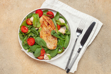 Fresh salad - spinach leaves, tomato, mushrooms, chards leaves and chicken fillet grill in a plate on the table. Top view. Healthy diet food.