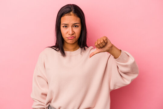 Young latin woman isolated on pink background  showing thumb down, disappointment concept.
