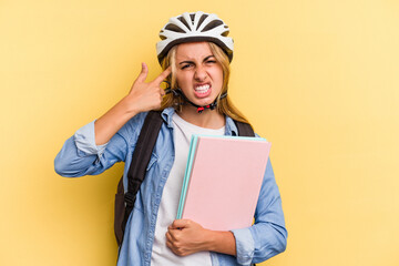 Young caucasian student woman wearing a bike helmet isolated on yellow background  showing a disappointment gesture with forefinger.