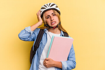 Young caucasian student woman wearing a bike helmet isolated on yellow background  being shocked, she has remembered important meeting.