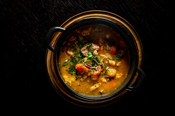 Pichelsteiner meat soup with vegetables in bowl on wooden table background
