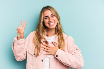 Young caucasian blonde woman isolated on blue background  taking an oath, putting hand on chest.