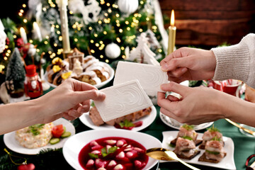 Sharing with Christmas Eve wafer at the festive table - obrazy, fototapety, plakaty