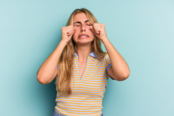 Young caucasian blonde woman isolated on blue background  whining and crying disconsolately.