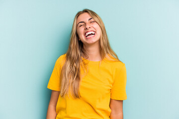 Young caucasian blonde woman isolated on blue background  relaxed and happy laughing, neck stretched showing teeth.