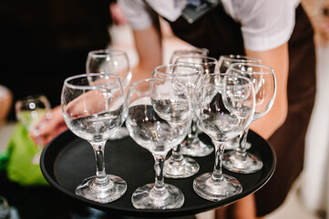 The waiter takes the empty glasses with the tray. Hands Puts on the table for the guests in the restaurant.