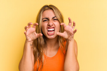 Young caucasian blonde woman isolated on yellow background  upset screaming with tense hands.