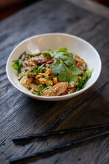 thai noodles in a white plate on a brown background with chopsticks
